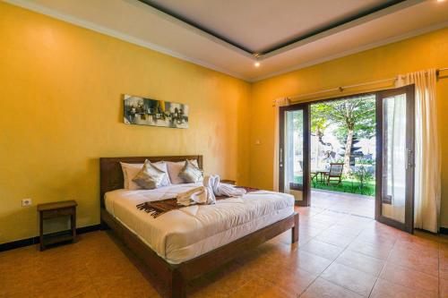 1 dormitorio con 1 cama y puerta corredera de cristal en Grand Ball Beach Garden, en Nusa Penida