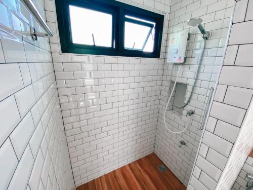 baño con ducha de azulejos blancos y ventana en เดอนาปัว วิลล่า en Ban Chalaeng