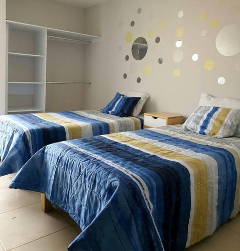 a bedroom with two beds with blue and yellow sheets at Depa/Loft Puebla SLP a 15 min del centro histórico in San Luis Potosí