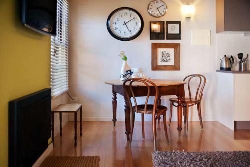 a dining room with a table and chairs and a clock on the wall at Circa Ruby Mint Daylesford in Daylesford