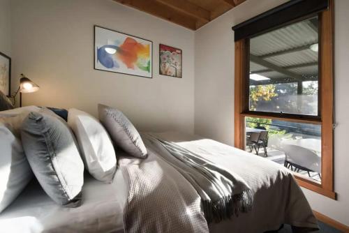 a bedroom with a bed with white pillows and a window at The Lodge Daylesford in Hepburn