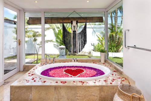 a bathroom with a large tub filled with pink flowers at Villa Puri Balangan in Uluwatu