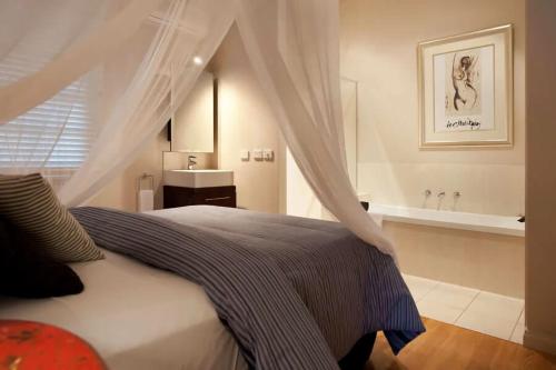 a bedroom with a bed and a tub in a bathroom at Circa Red London Daylesford in Daylesford