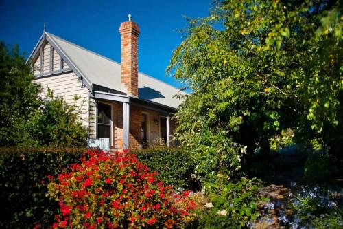a house with a brick chimney and flowers at Circa Red London Daylesford in Daylesford