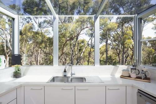 a kitchen with a sink and large windows at The Bird House - Hepburn Springs Daylesford in Hepburn Springs