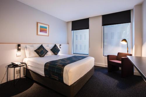 a hotel room with a bed and a desk and a chair at CitiClub Hotel Melbourne in Melbourne