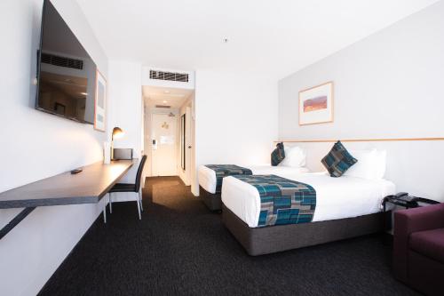 a hotel room with two beds and a television at CitiClub Hotel Melbourne in Melbourne