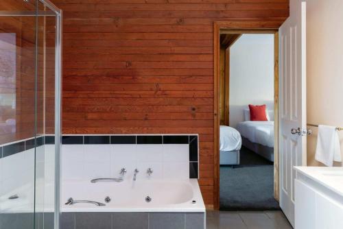 a bathroom with a bath tub and a bedroom at Halina Daylesford in Daylesford