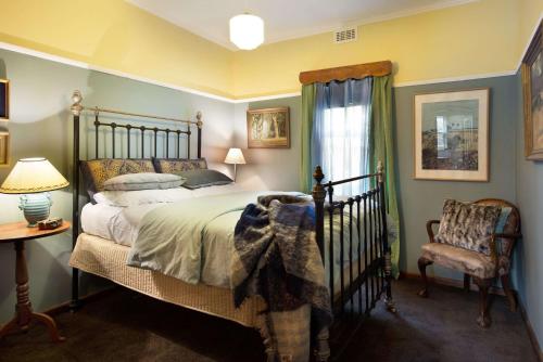 a bedroom with a bed and a chair at The Raglan Daylesford in Daylesford