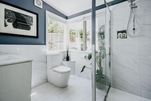 a white bathroom with a shower and a toilet at Candlebark Daylesford in Daylesford
