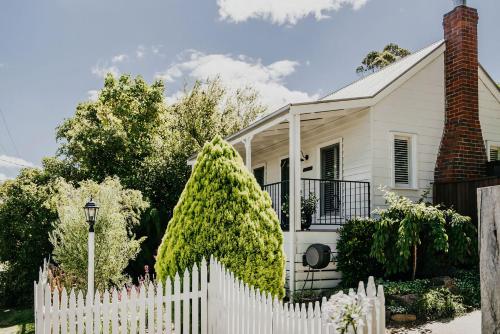 a white picket fence in front of a white house at Candlebark Daylesford in Daylesford