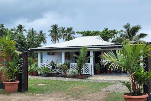 a white house with palm trees in front of it at Maddy's House in Maatea