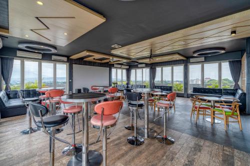 a restaurant with tables and chairs and windows at Ascent Hotel & Cafe Malang in Malang
