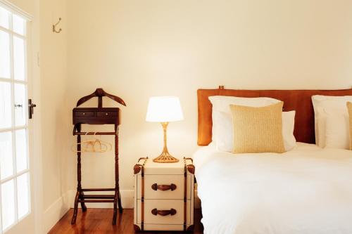 a bedroom with a bed with a lamp and a suitcase at Mount William Station in Willaura