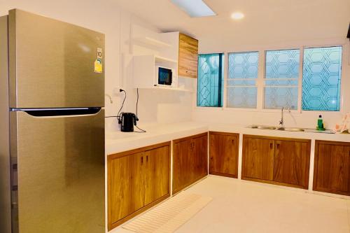 a kitchen with wooden cabinets and a stainless steel refrigerator at Home Story Hostel Chiang Mai in Chiang Mai