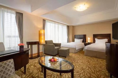 pokój hotelowy z 2 łóżkami i salonem w obiekcie Furama Hotel Dalian w mieście Dalian