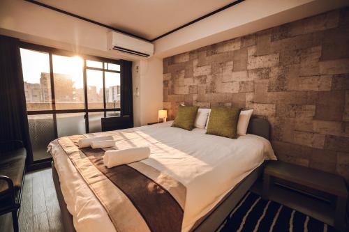 大阪市にあるLIBERTY PALACE Apartment3のレンガの壁のある部屋にある大きなベッド