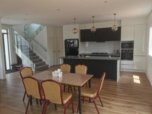uma cozinha e sala de jantar com mesa e cadeiras em Stunning Stay In Papatoetoe Auckland em Auckland
