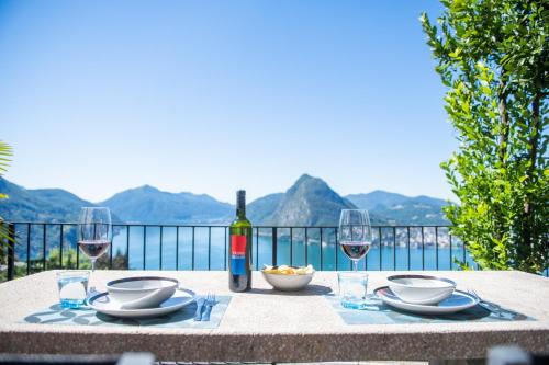 a table with a bottle of wine and two glasses at Lugano Vista Lago, Jacuzzi, Montagna a 5 stelle in Aldesago