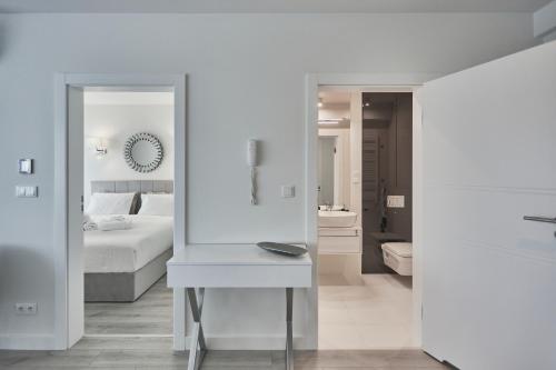 een witte slaapkamer met een bed en een spiegel bij Wave Międzyzdroje Resort & SPA - Sea&Forest View B644 in Międzyzdroje