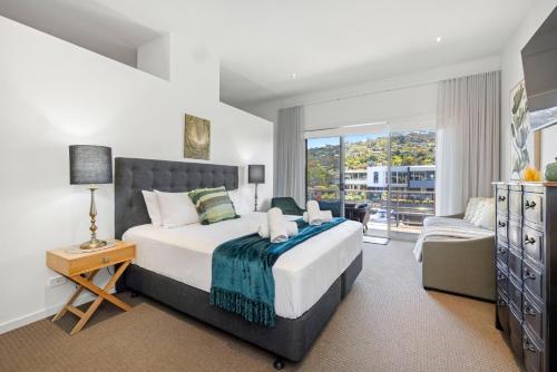 Un dormitorio con una cama y una silla y una ventana. en The Cove - Luxury Waterfront Accommodation, en Safety Beach