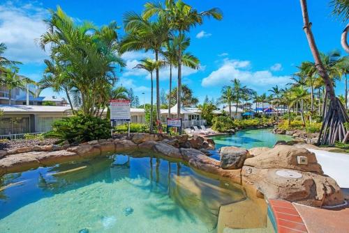 - un toboggan aquatique dans un complexe avec des palmiers dans l'établissement Alex Heads Beachfront Resort King Bed Studio Room, à Alexandra Headland