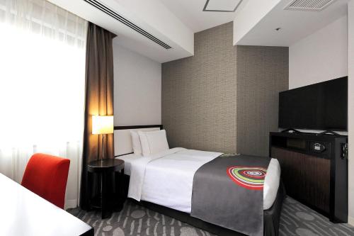 a hotel room with a bed and a flat screen tv at The Royal Park Hotel Fukuoka in Fukuoka