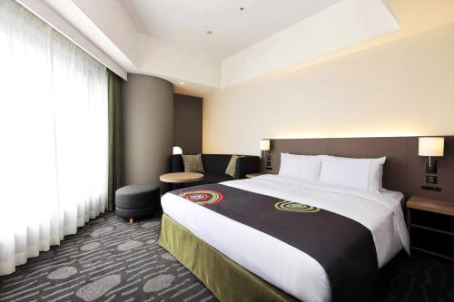a hotel room with a large bed and a chair at The Royal Park Hotel Fukuoka in Fukuoka