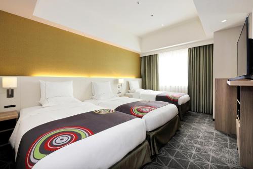 a hotel room with two beds and a television at The Royal Park Hotel Fukuoka in Fukuoka