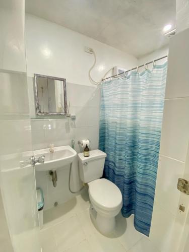 a white bathroom with a toilet and a sink at Saltitude Dive & Beach Resort in Mabini