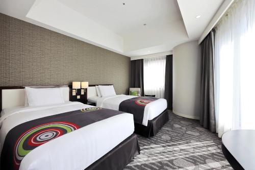 a hotel room with two beds and a window at The Royal Park Hotel Fukuoka in Fukuoka