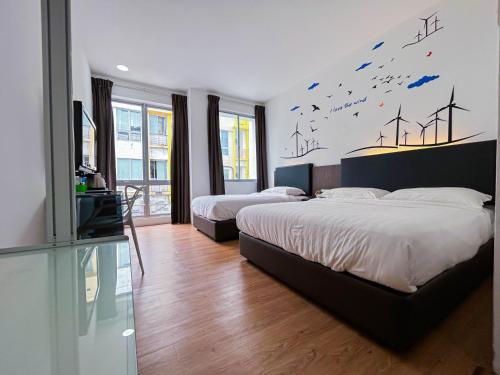 a bedroom with two beds and a mural of wind turbines at Cel Hotel in Skudai
