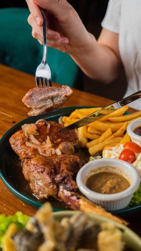 a plate of food with meat and french fries at Cel Hotel in Skudai