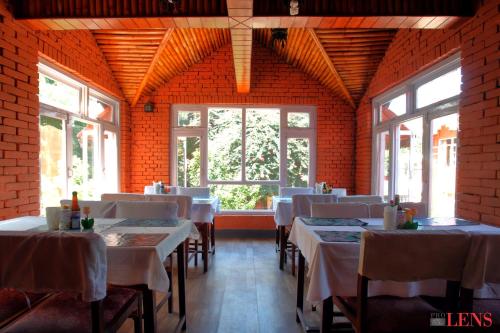 a dining room with tables and chairs and windows at Hotel Melungtse & Apartment in Kathmandu
