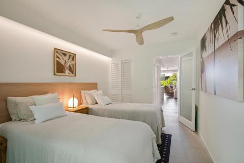 2 letti in una camera con pareti bianche e soffitto di The Cove Noosa - Apartment 13 a Noosa Heads