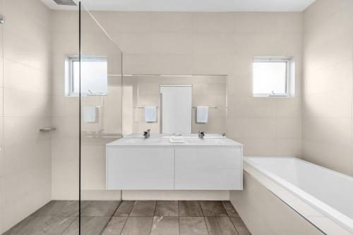 a white bathroom with a sink and a shower at Bamboo Beachhouse in Berrara