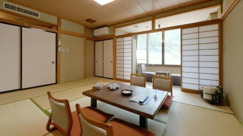 a room with a table and chairs and windows at Hotel Koryu in Fujikawaguchiko