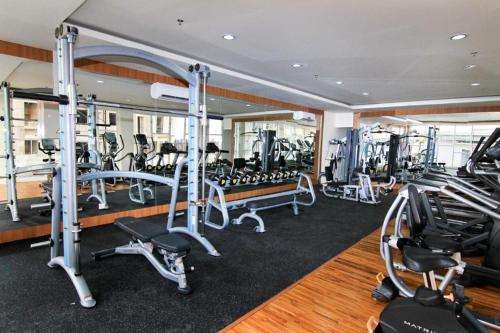 a gym with several treadmills and ellipticals at TripleQ Room 2BR Vidaview Apartment in Makassar