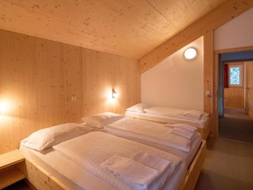 two twin beds in a room with wooden walls at Chalet Alpenpark Turracherhöhe 4 in Turracher Hohe