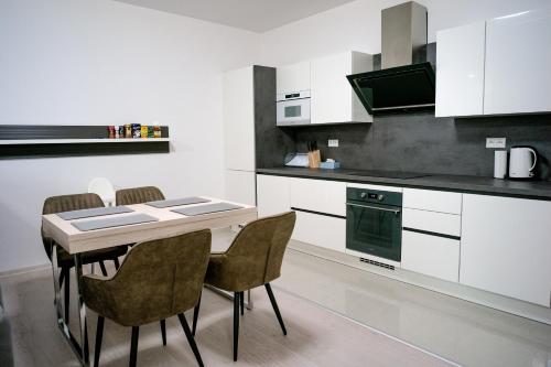 - une cuisine avec des placards blancs, une table et des chaises dans l'établissement AH Lahoda, à Košice