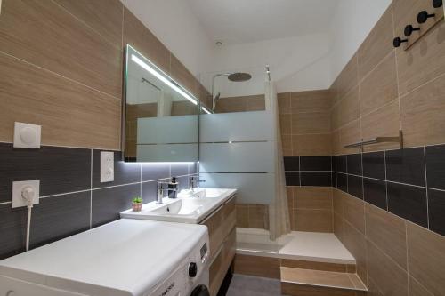 La salle de bains est pourvue d'un lavabo, d'un miroir et d'une baignoire. dans l'établissement Appartement Quai Jean Jaurès Le Panorama, à Mâcon