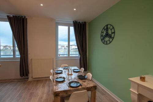 une salle à manger avec une table, des chaises et une horloge dans l'établissement Appartement Quai Jean Jaurès Le Panorama, à Mâcon