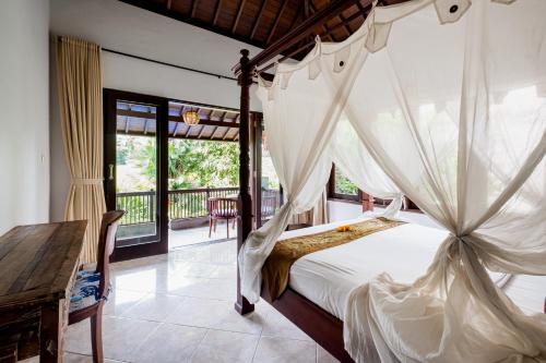 a bedroom with a canopy bed and a balcony at Pukakoo Villas and Suite by Supala in Ubud