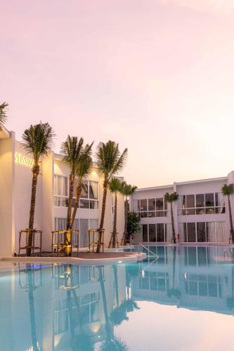 a pool with palm trees in front of a building at The Gems Mining Pool Villas Pattaya in Nong Prue