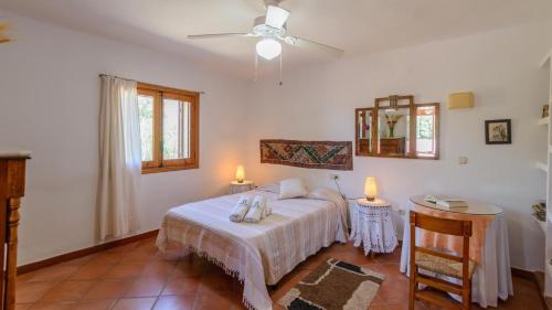 1 dormitorio con 1 cama, 2 mesas y ventilador de techo en Villa Jacaranda de Órgiva by Ruralidays, en Órgiva