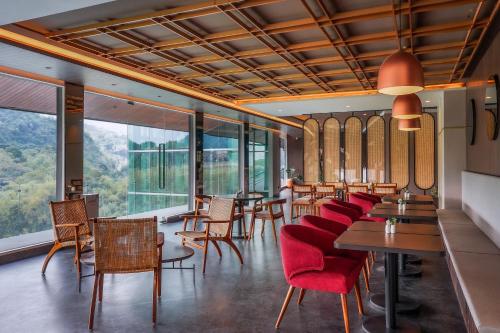 Forest Hills Hotel في Soreang: مطعم بطاولات وكراسي ونوافذ كبيرة