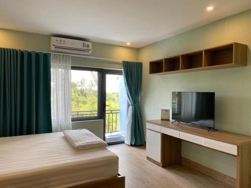 Schlafzimmer mit einem Bett, einem TV und einem Fenster in der Unterkunft Coco Homestay in Phu Quoc