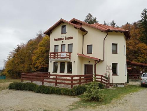 a large white house with a fence in front of it at Pensiunea Rozelor Sâmbăta de Sus in Sîmbăta de Sus