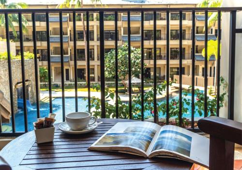um livro aberto sobre uma mesa com uma chávena de café em Radisson Resort and Suites Phuket em Praia de Kamala