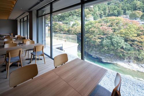 a cafeteria with tables and chairs and a large window at Minakami Onsen Aratashi Minakami in Minakami
